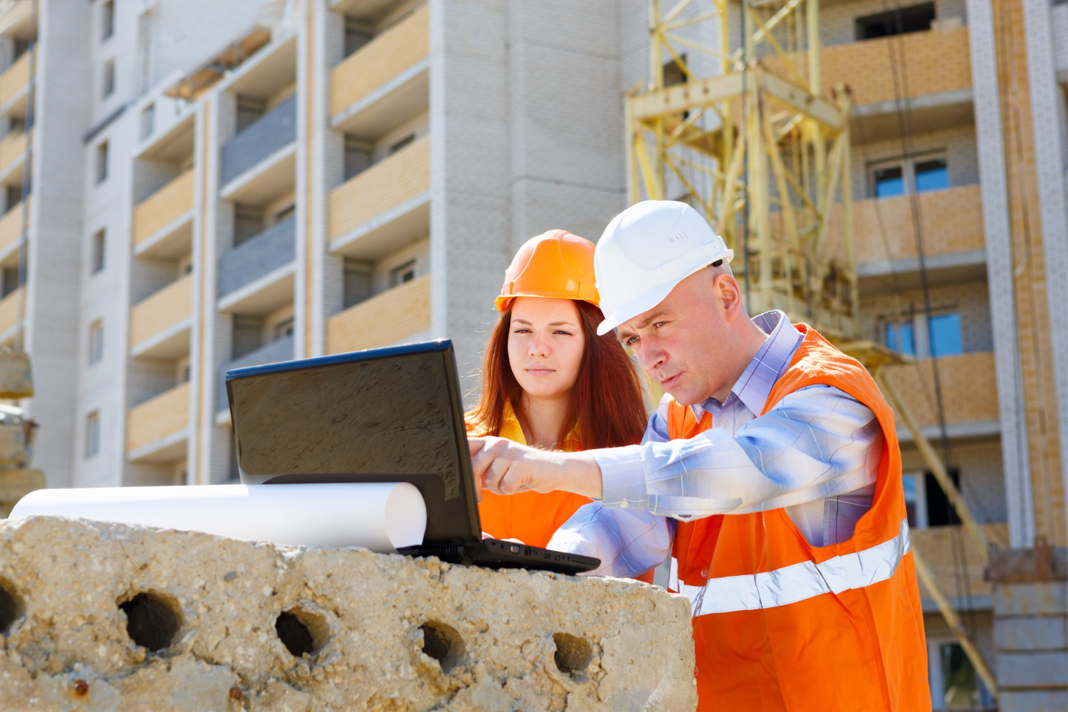 two construction workers look at a laptop on project site medical case management mobile medical corporation